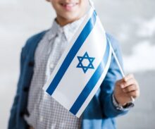 cropped view of smiling jewish boy holding flag of israel